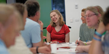 Woman in red smiling at a group of people