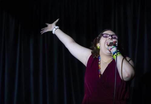 black and white photo of woman holding a microphone and her otherhand stretched out